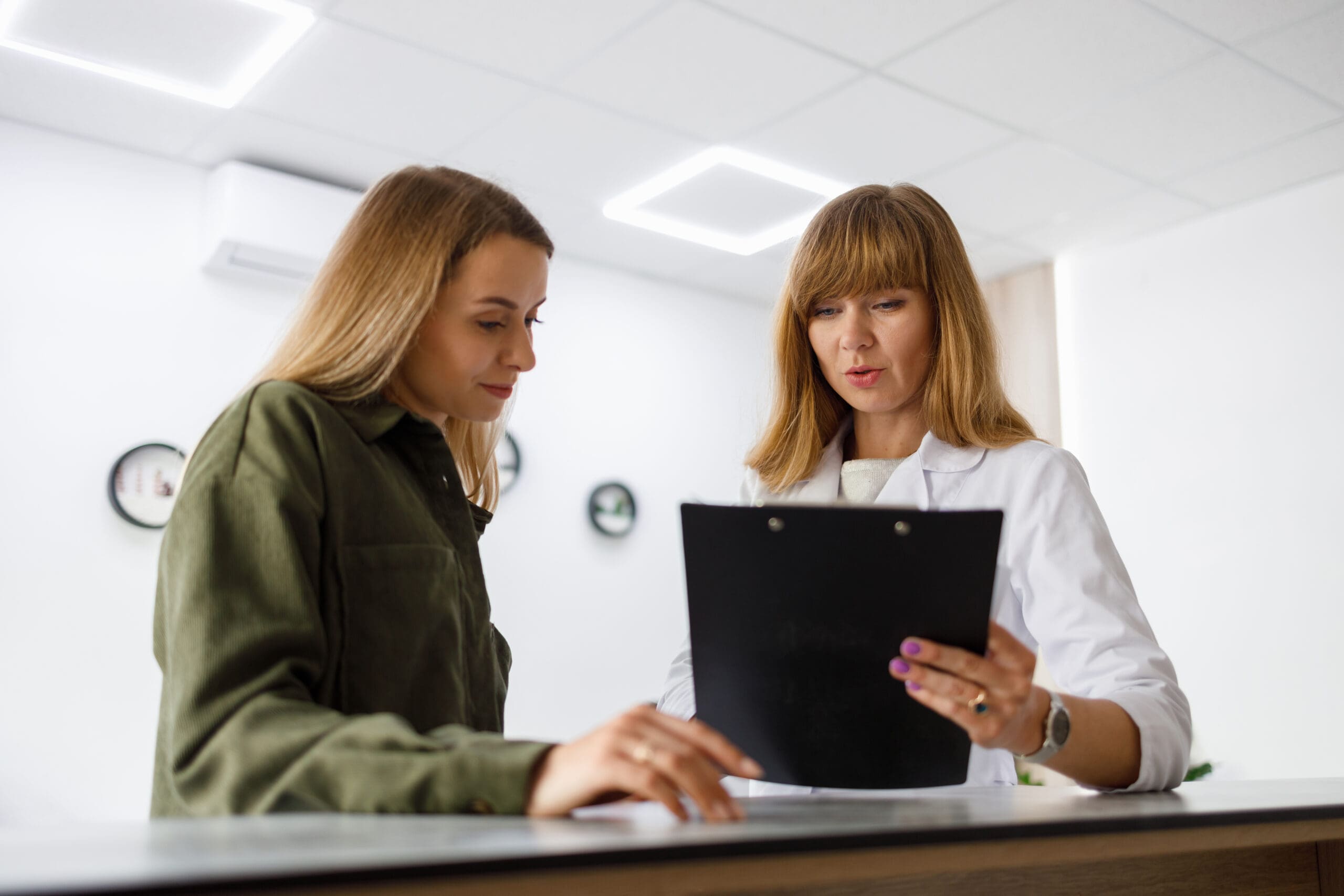 A woman discussing with a medical professional, "Why Expecations Women's Center"